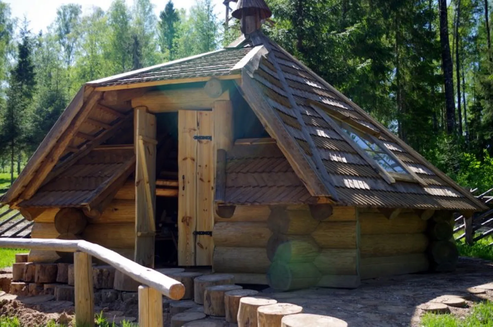 Ümarpalgist saun kõrge viilkatuse ja avatud sissepääsuga, metsa serval, kiviäärse rajaga. Töö tegi Ööbiksaare Palkmajad.