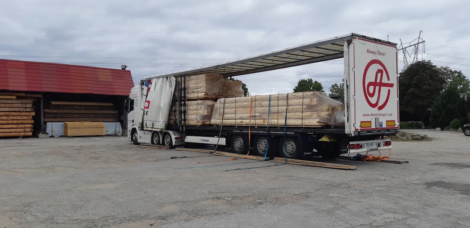 Ahola Transporti veoauto laaditud palkmaja seinapakettidega Laitse tootmisõuel. Töö tegi Palkehitus.