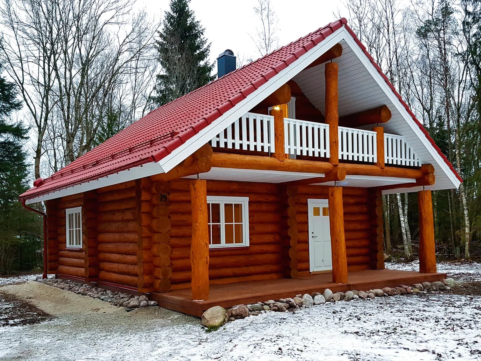 Ümarpalkmaja rõduga, valgustatud aknad, talveõhtune vaade. Töö tegi Palkmaja Ehitus.