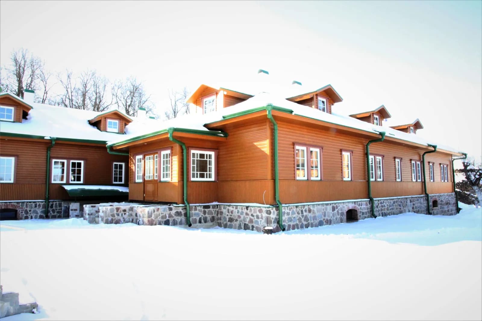 Pikk oranžikas puithoone rohelise katuse ja mitme katuseaknaga, lumi maas. Töö tegi Ritsu.