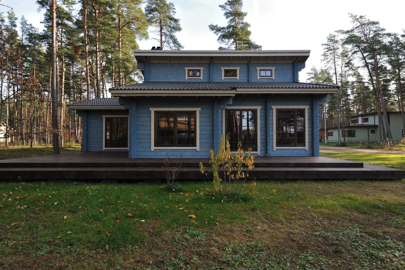 Modernne sinakastoonis palkmaja suurte akende ja puitterrassiga. Töö tegi Ritsu.
