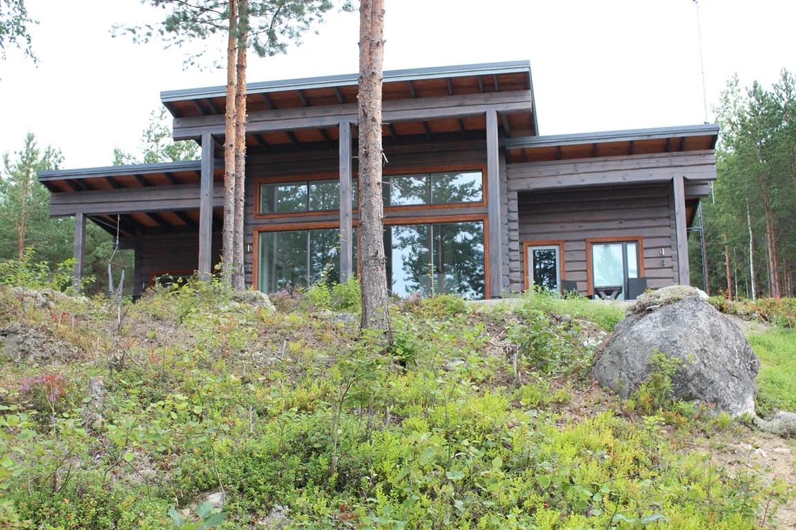 Moodne põhjamaine palk-posttalastik Mäntyharjus Soomes, lagipunktist lagipunktini klaasitud viiluosaga, sammaldunud metsaserva krundil. Töö tegi Eesti Käsitöö Palkmajad.
