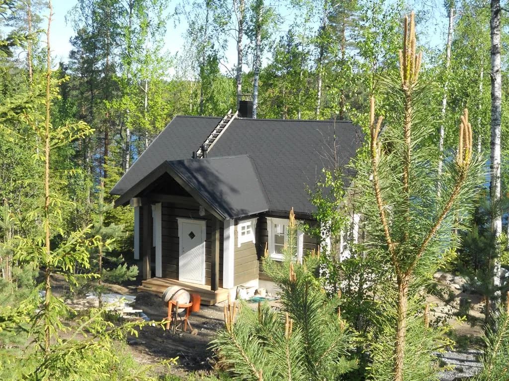 Väike tumedaks värvitud ühekorruseline suvila metsas veekogu lähedal, valminud väljanägemisega. Töö tegi Eesti Käsitöö Palkmajad.